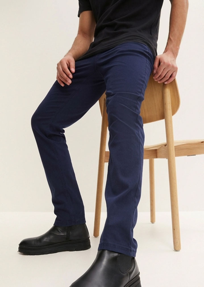 Schwarzes T-Shirt, blaue Hose und moderne schwarze Stiefeletten.