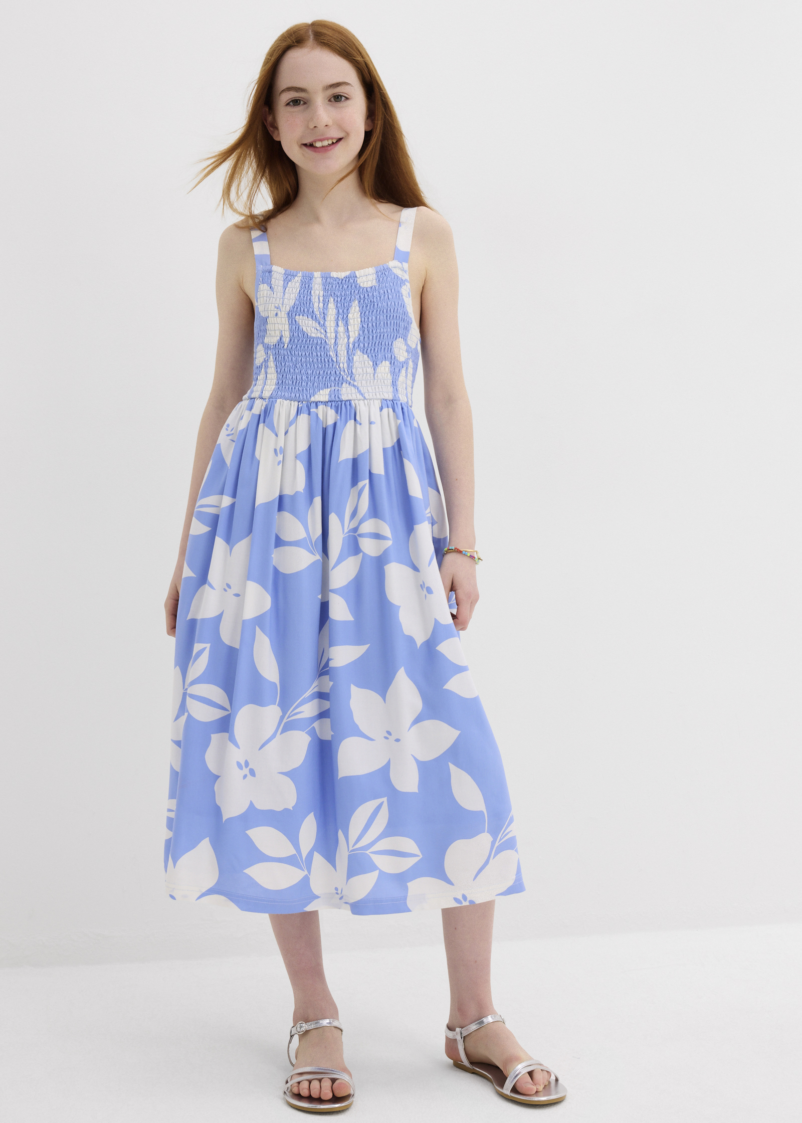 Mädchen trägt ein hellblaues Sommerkleid mit weißen Blüten.