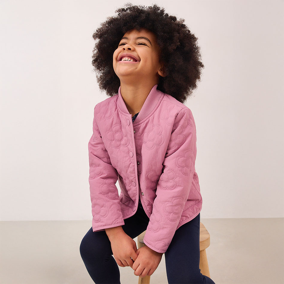 Eine rosafarbene Jacke mit Knöpfen über einem dunklen Oberteil.