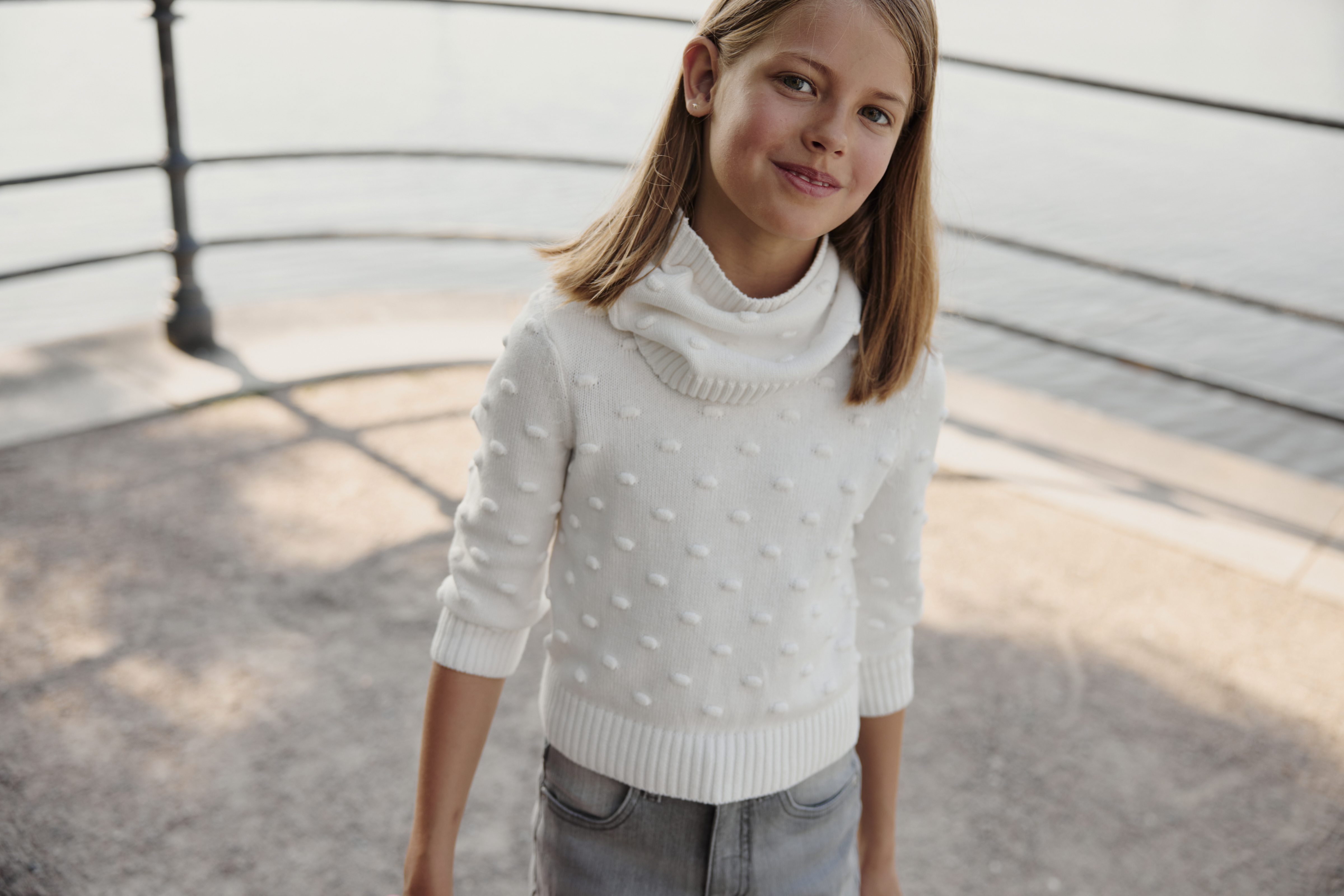 Weicher weißer Rollkragenpullover, kombiniert mit lässiger grauer Hose, strahlt Komfort und Stil aus.