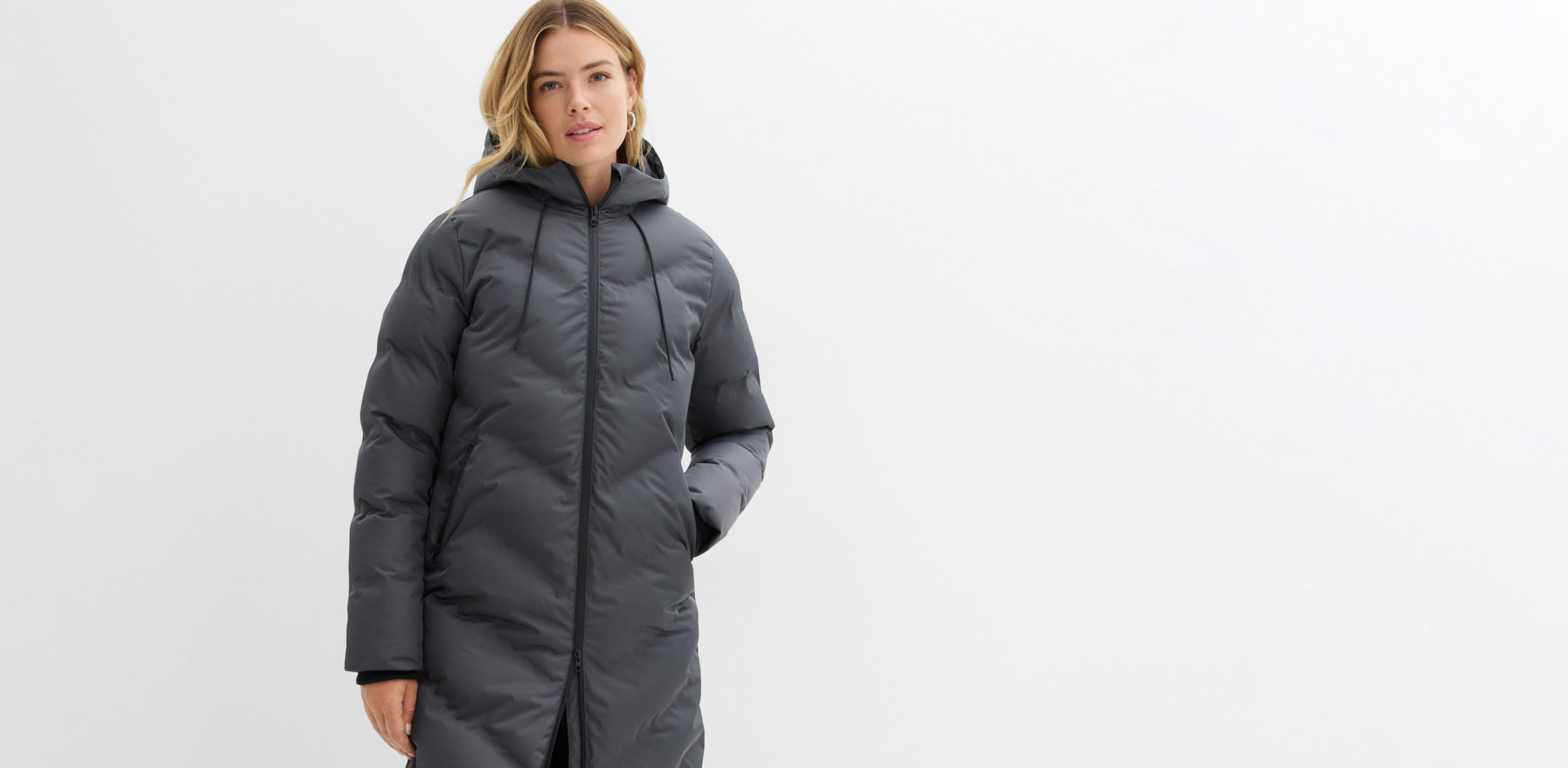 Langer, grauer Wintermantel mit Kapuze und Reißverschluss.