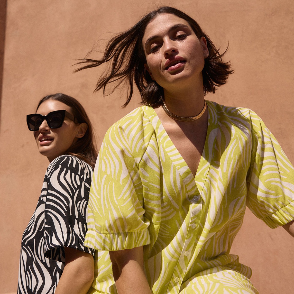 Sommerliche Mode: Ein leuchtendes gelbes Kleid mit Muster und ein gestreiftes Hemd.