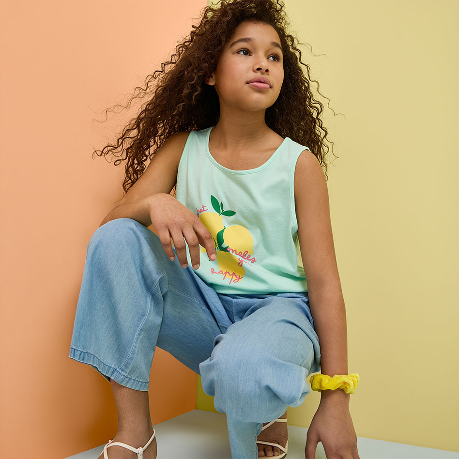 Mintgrünes Zitronen-Top und weite Jeans, ergänzt durch weiße Sandalen und gelbes Scrunchie.