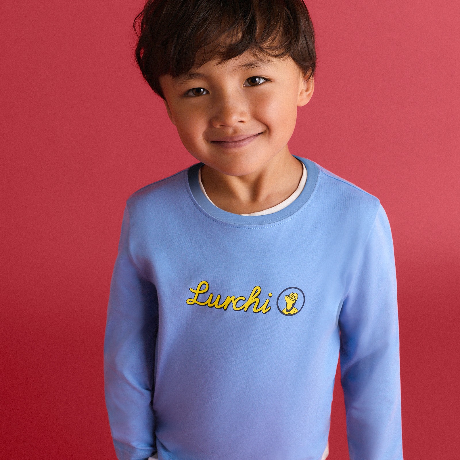 Der Junge trägt ein hellblaues Langarmshirt mit gelbem Lurchi-Schriftzug.