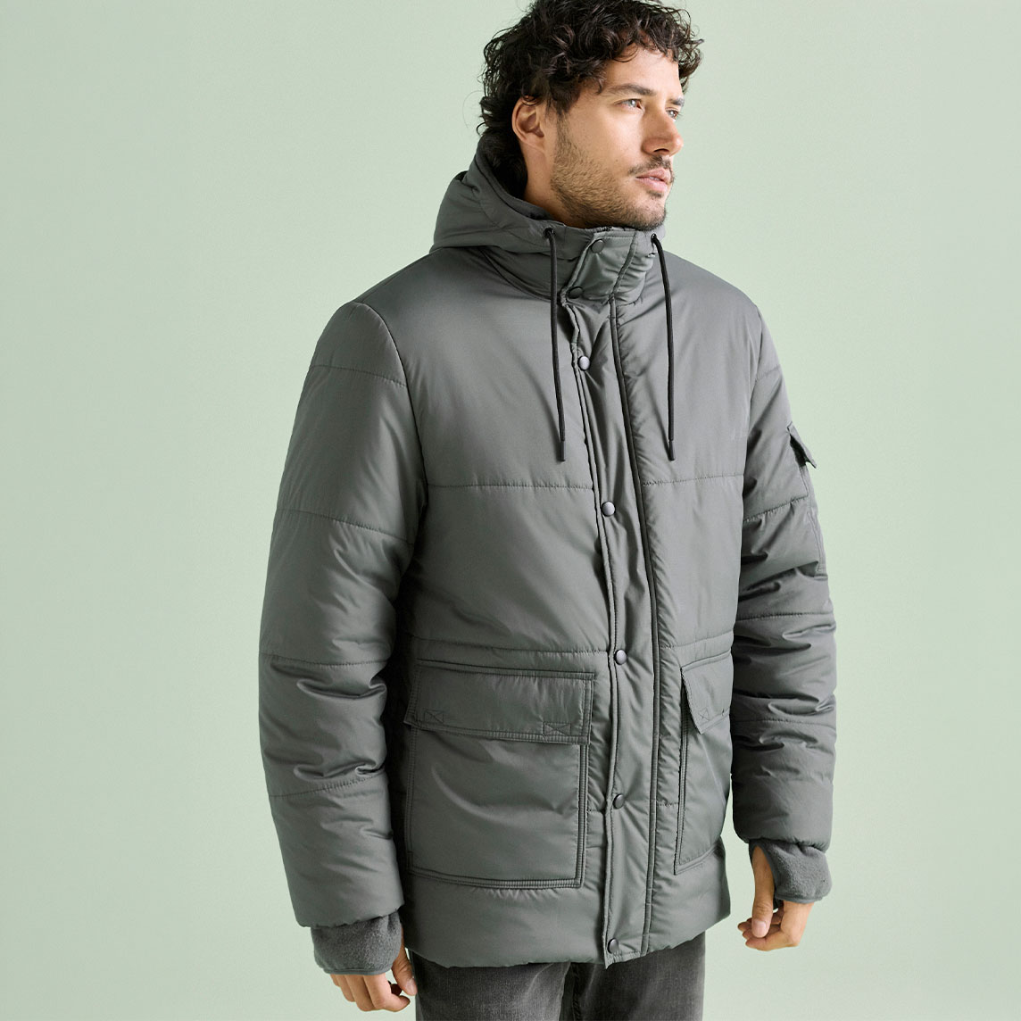 Graue wattierte Jacke mit Kapuze über dunkler Jeans.