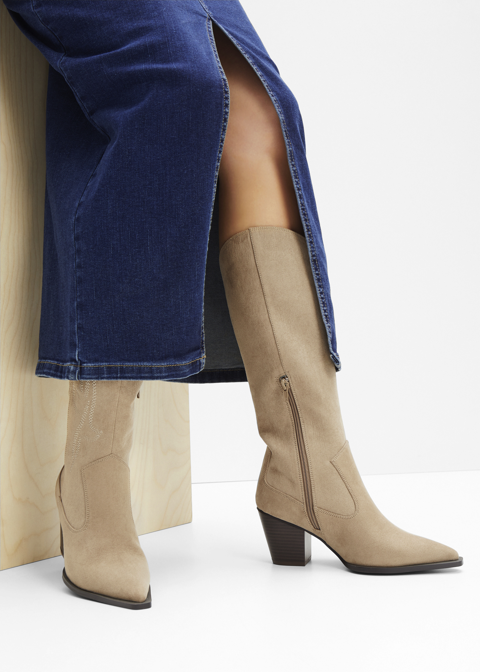 Blauer Jeansrock kombiniert mit beigen Cowboy-Stiefeln mit Absatz.