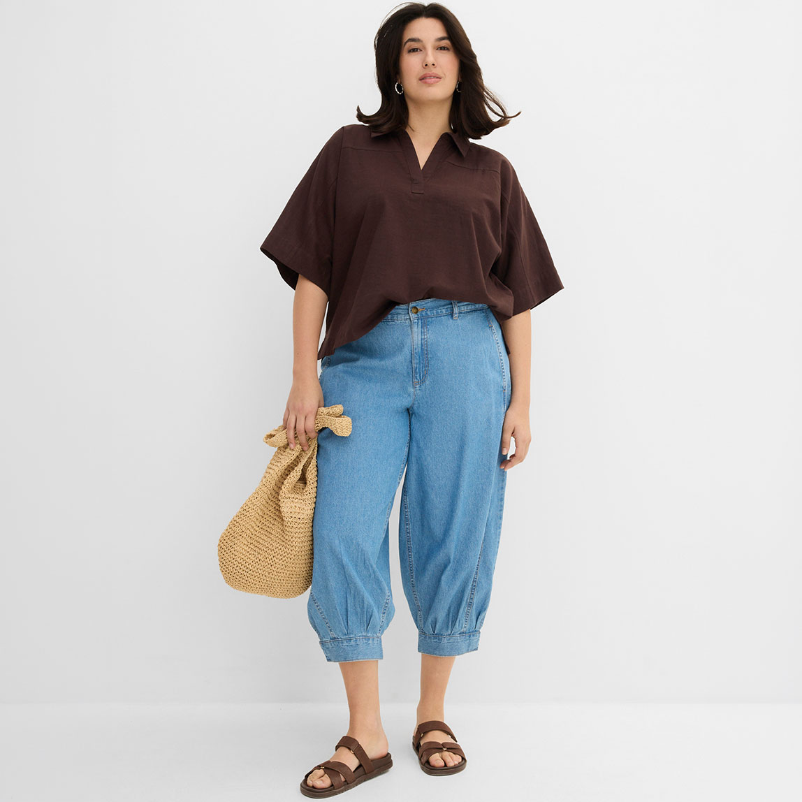 Lässige braune Bluse kombiniert mit weiten Jeans-Culottes und einer geflochtenen Tasche.