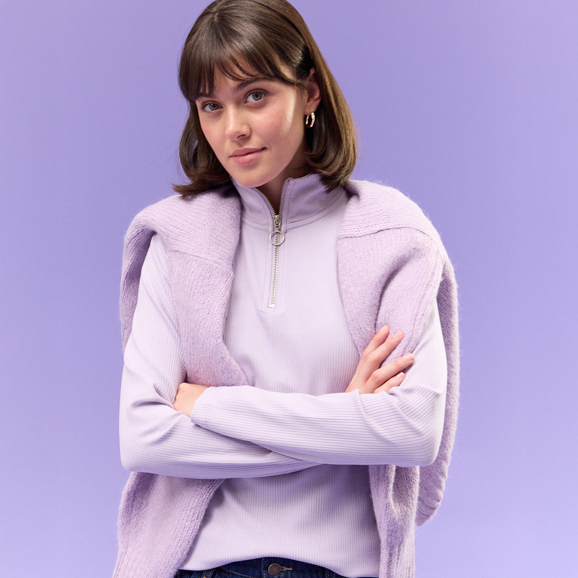 Lila Rippshirt mit Reißverschluss, kombiniert mit dunkler Jeans.