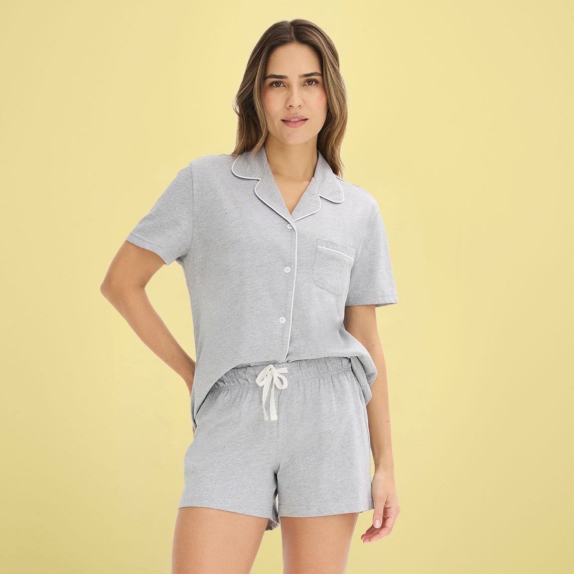 Frau trägt grauen Pyjama mit kurzärmliger Bluse und passenden Shorts mit Kordel.