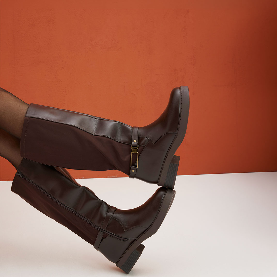 Braune Stiefel mit Riemen und Schnallen, kombiniert mit eleganten schwarzen Strumpfhosen.