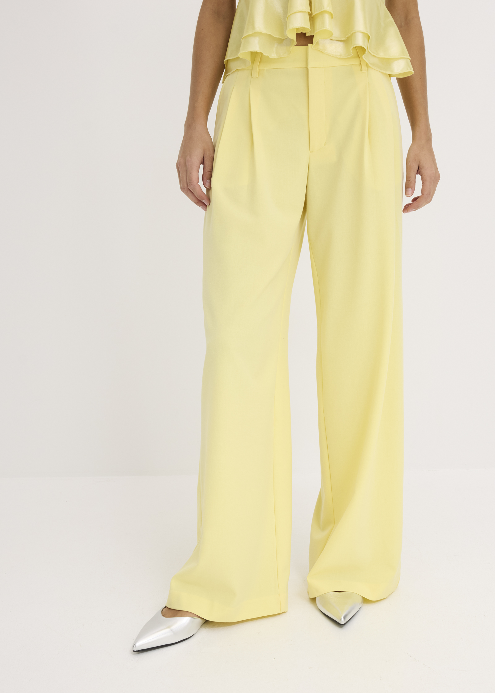 Helle gelbe Hose, passendes Oberteil und schicke spitze Silberschuhe.
