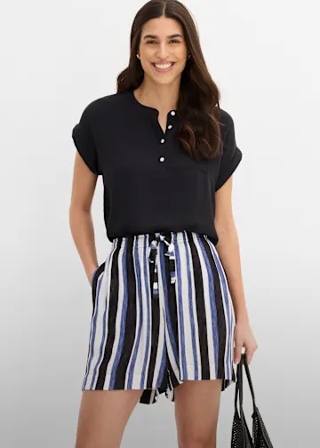 Schwarzes Kurzarm-Oberteil und gestreifte Shorts in Blau, Weiß und Schwarz.