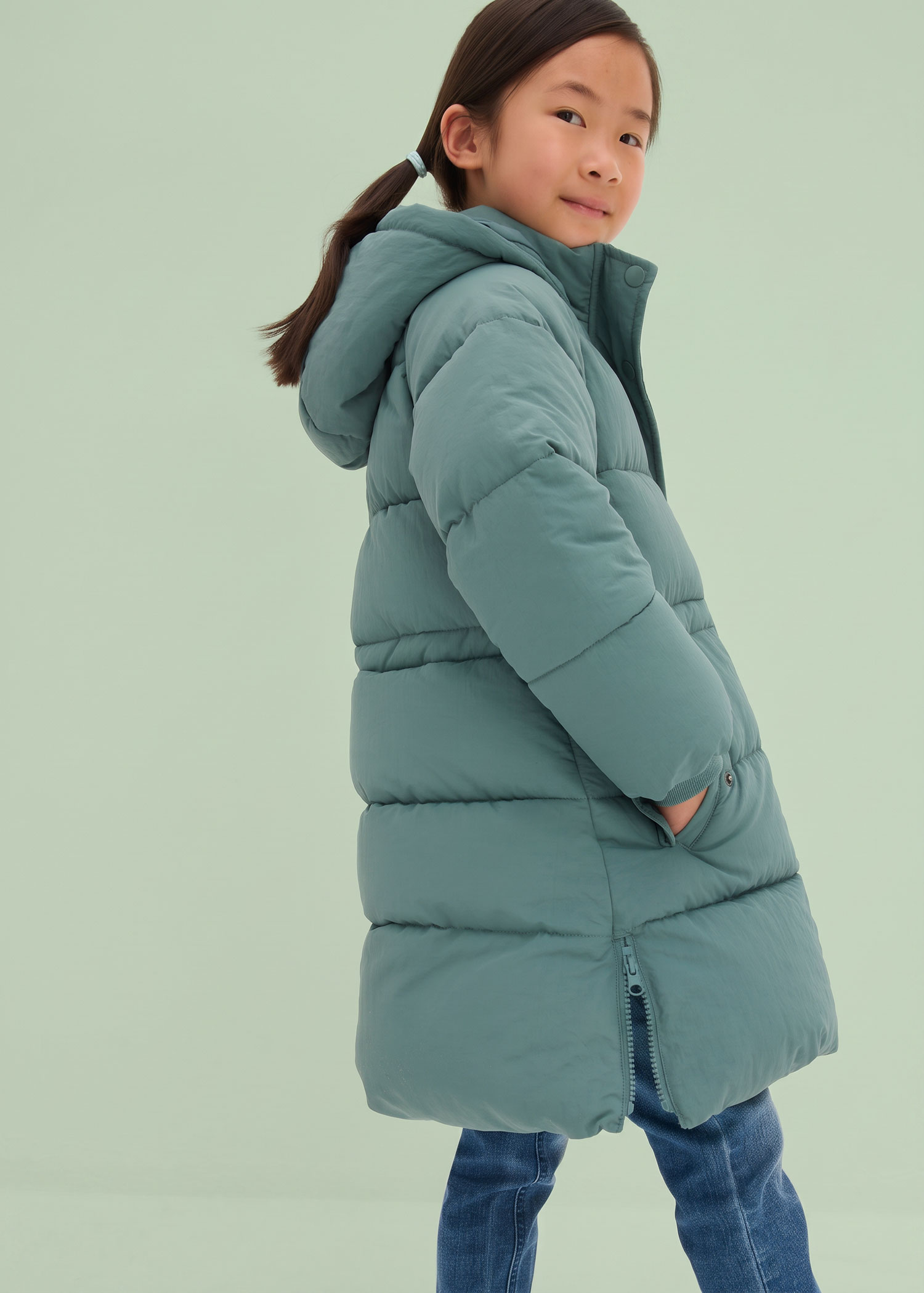 Mädchen in langer, mintgrüner Pufferjacke.