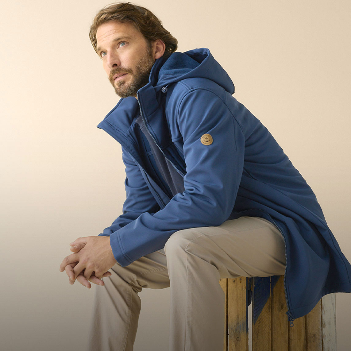 Blauer Kapuzenparka, beige Hose und stylische Sneaker. 