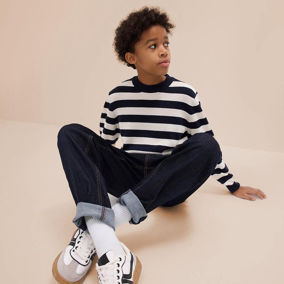 Gestreifter Pullover und dunkle Jeans kombiniert mit weißen Sneakers - lässiger Alltagslook.