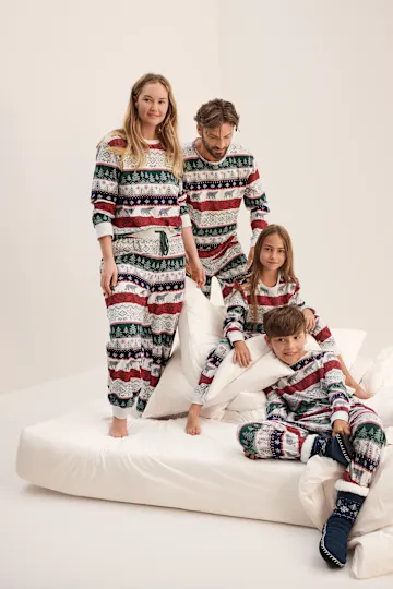 Die Familie trägt gemütliche, festliche Weihnachtspyjamas mit Bäumen und Tiermotiven.