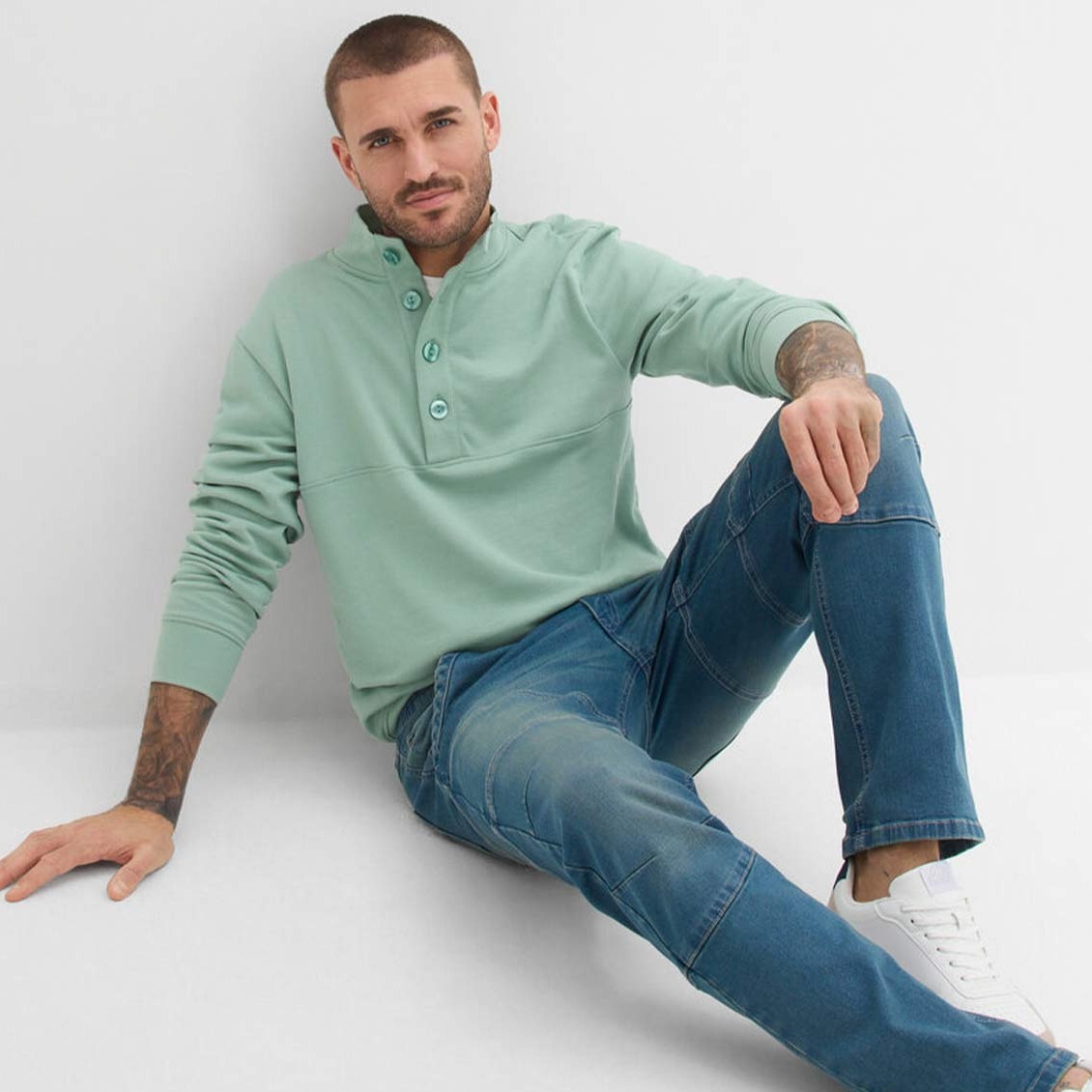 Mintgrüner Sweater mit Reißverschluss am Kragen, kombiniert mit blauen Jeans.