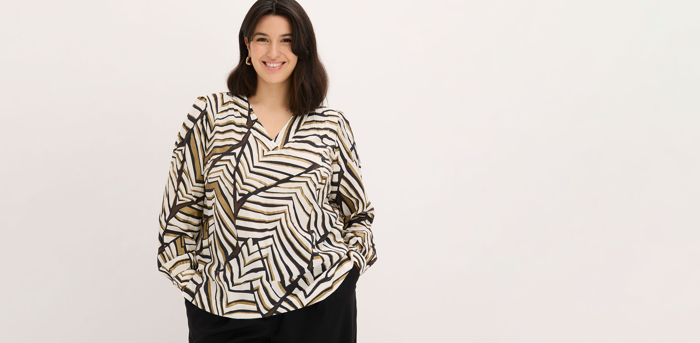 Bluse mit grafischem Muster und schwarze Hose.
