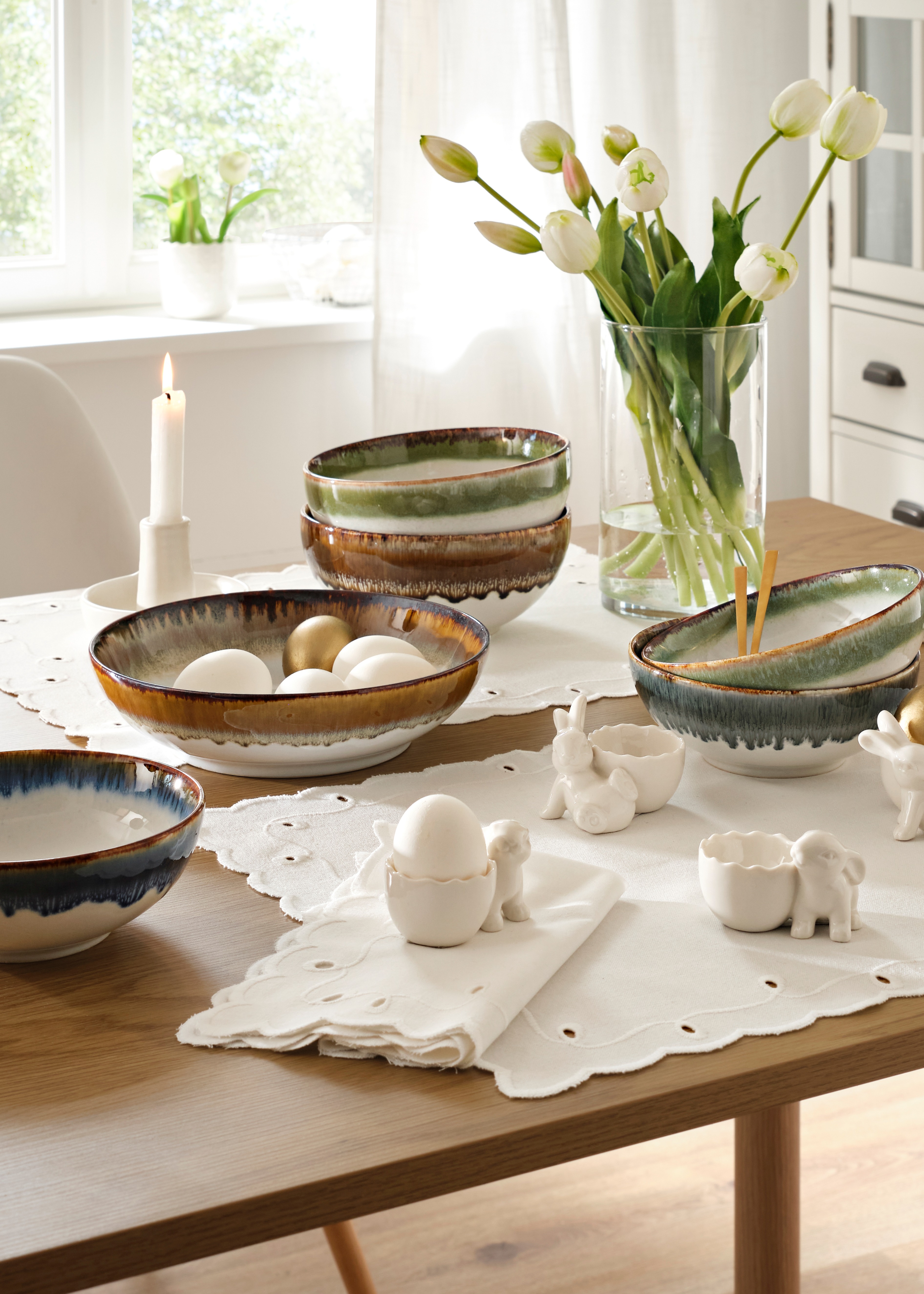 Gedeckter Tisch mit Blumenvase und Kerze  auf weißer Spitzendecke.