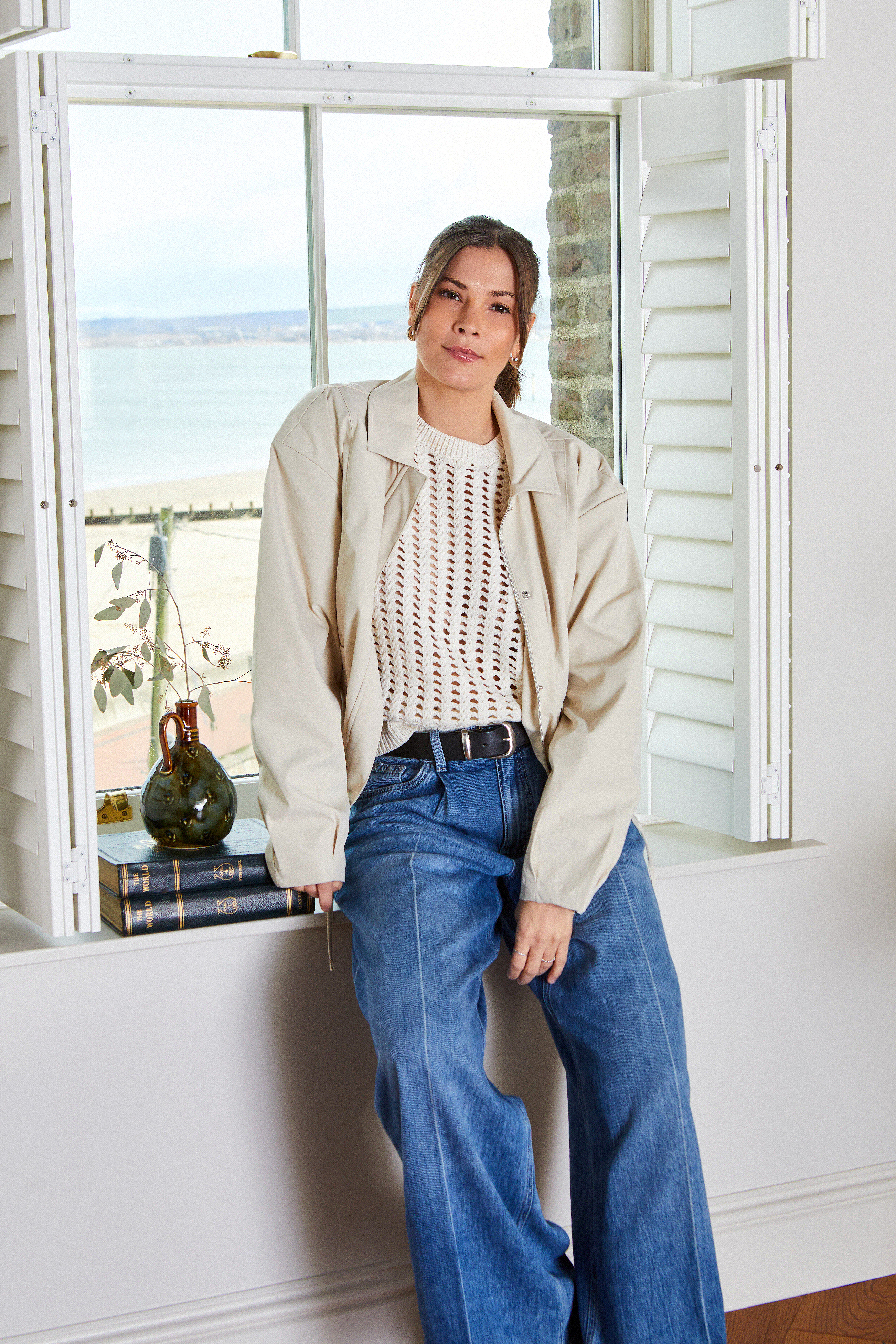 Cremefarber Blousson über luftigem Häkeltop, kombiniert mit weiten Jeans.