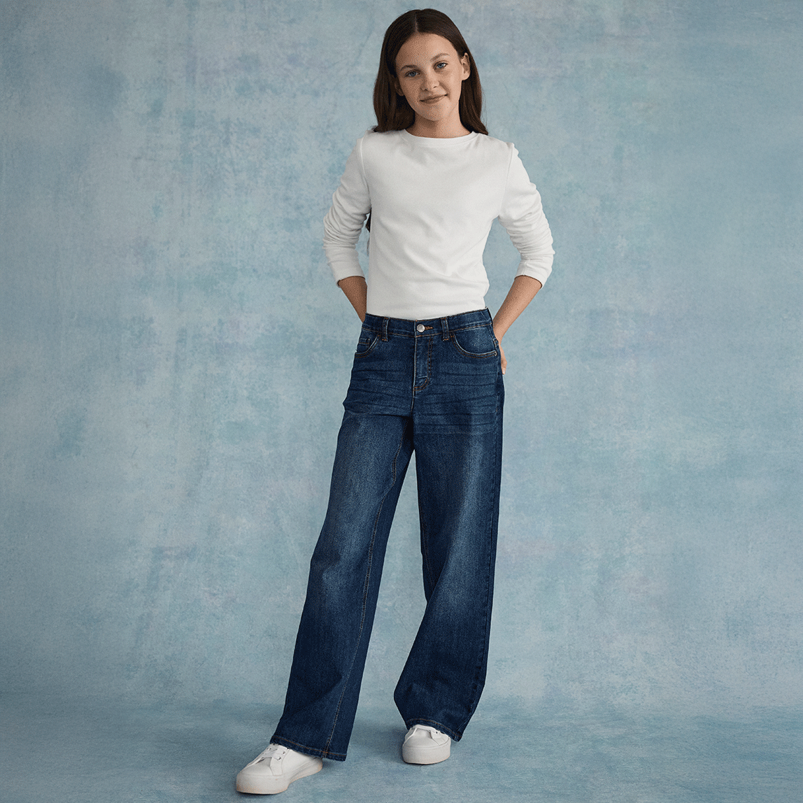 Weißes, strukturiertes Oberteil kombiniert mit weiten Jeans und weißen Sneakers.