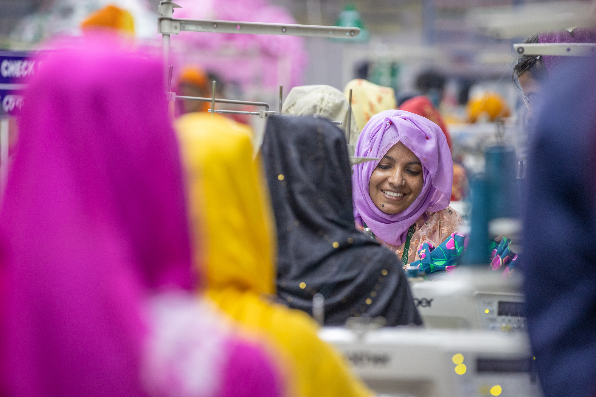 Bunte Kopftücher und Gewänder in einem Geschäft. Lebhafte Farben von Lila bis Gelb dominieren.