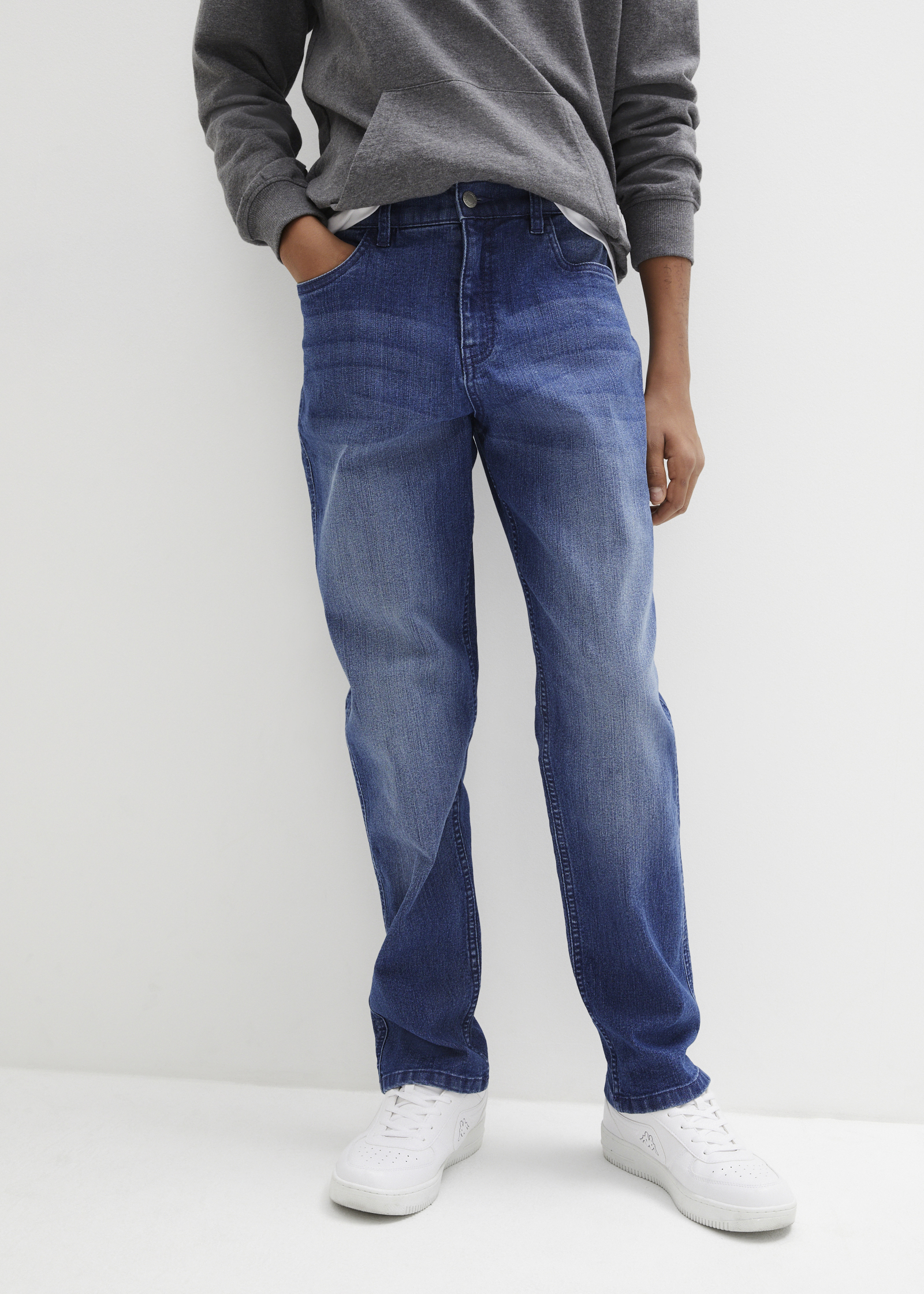 Grauer Hoodie, blaue Jeans und weiße Sneaker ergeben ein lässiges Outfit.