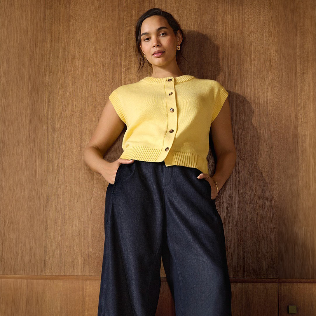 Gelbe Strickweste kombiniert mit einer weiten, dunkelblauen Hose.