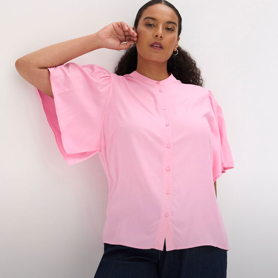Rosa Bluse mit weiten Ärmeln, Stehkragen und Knopfleiste.