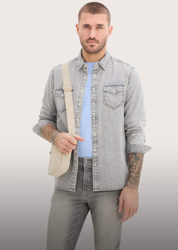 Helles Jeanshemd über hellblauem T-Shirt, dazu graue Jeans und eine beige Umhängetasche.