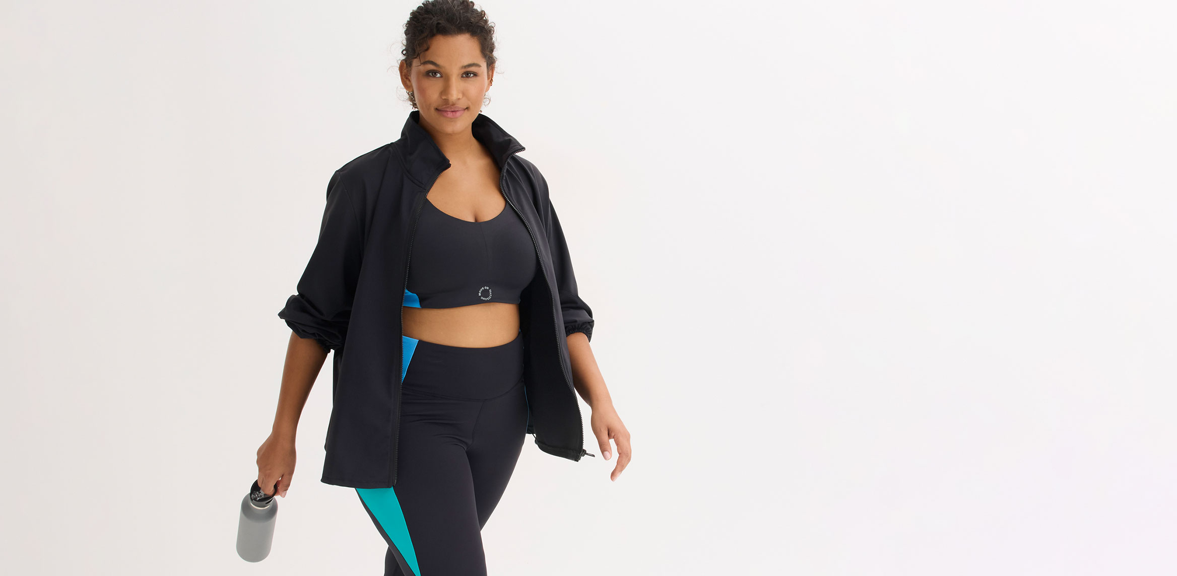 Dunkle Sportjacke, Sport-BH, farbige Leggings und Sneakers für aktiven Lifestyle.