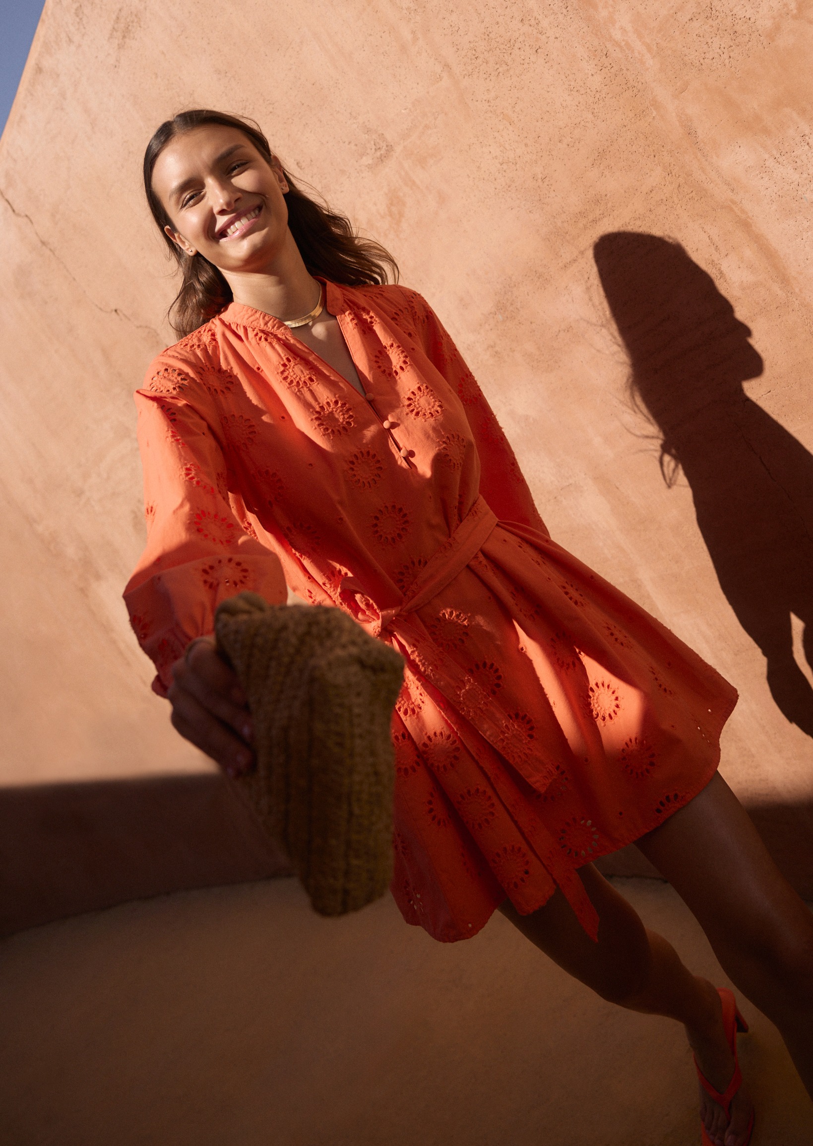 Lebendiges orangefarbenes Sommerkleid mit Spitzeneinsätzen strahlt Wärme und Leichtigkeit aus.