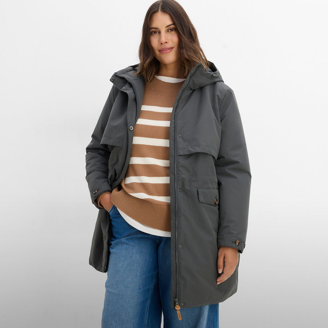 Graue Funktions-Jacke, gestreifter Pullover und bequeme Jeans.