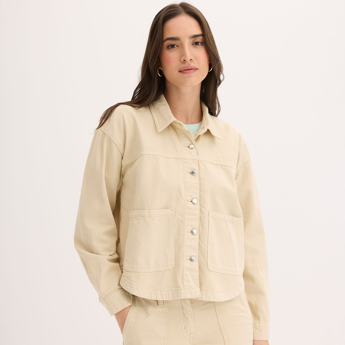 Cremefarbene Jacke mit Kragen, Knöpfen und Brusttasche. 