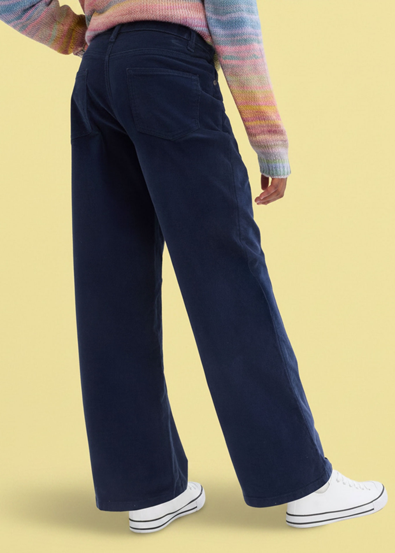Weite dunkelblaue Hose und weiße Sneaker.