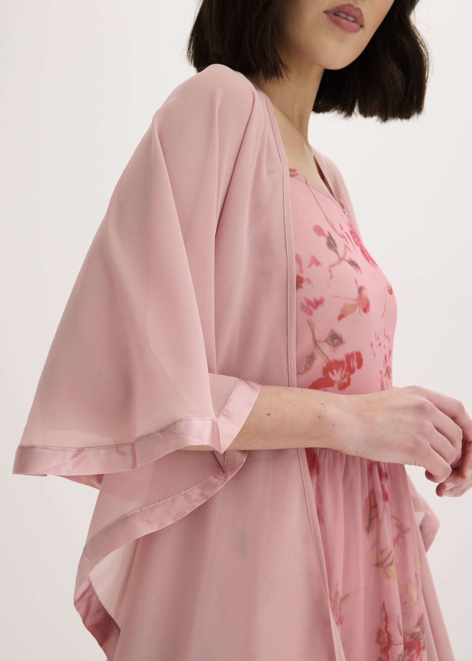 Leichter rosa Poncho über Sommerkleid mit Blumenmuster. 