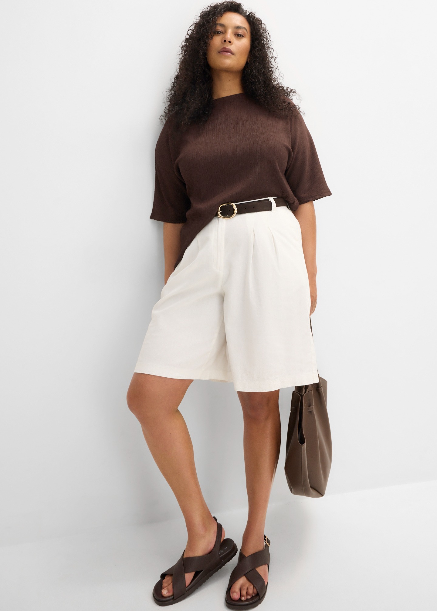 Dunkelbraunes Rippshirt, helle weite Shorts, Gürtel, dunkle Sandalen und passende Tasche.