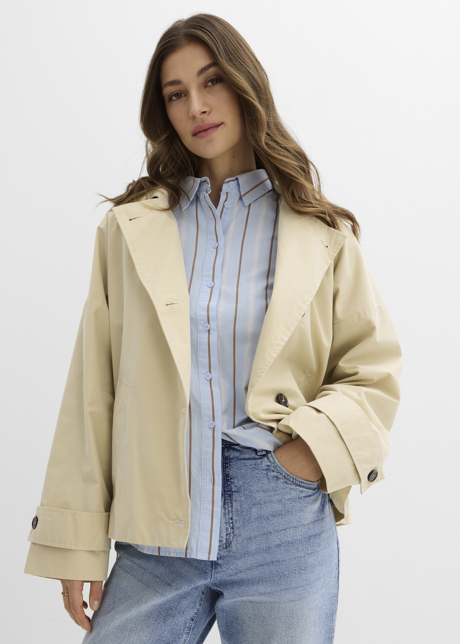 Beige Jacke, gestreiftes Hemd und blaue Jeans bilden einen lässigen Look.