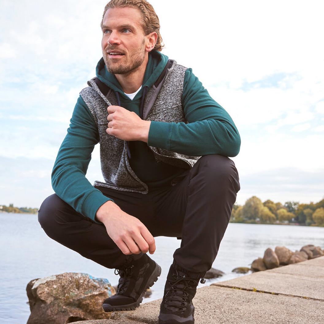 Grüner Sweater, dunkle Hose und praktische Weste für kühle Tage.