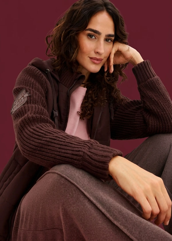 Warme Strickjacke mit gestrickten Ärmeln, rosa Top und passender Hose in Brauntönen.