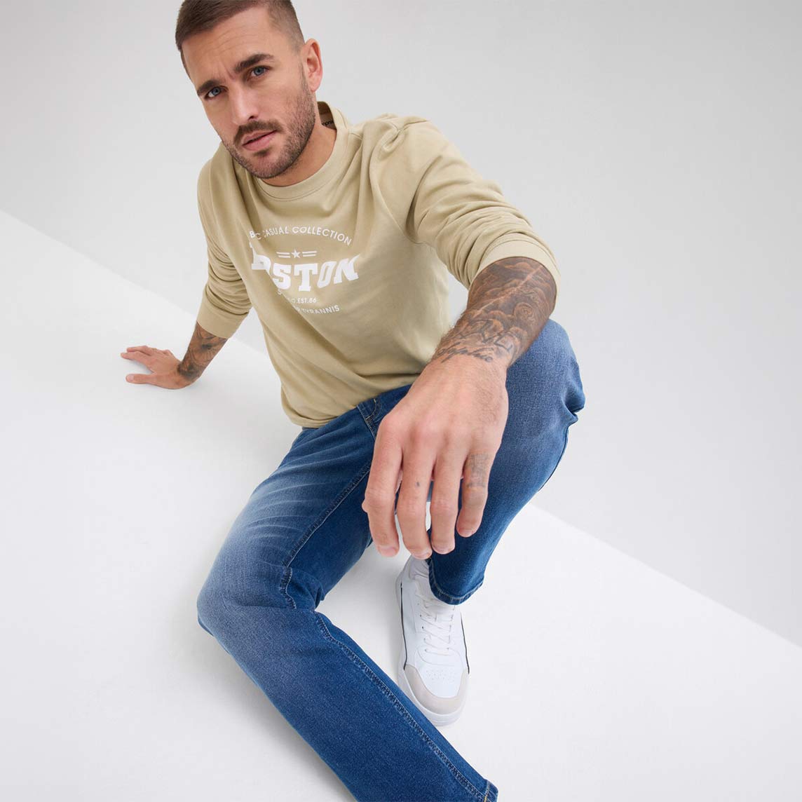 Regular-Fit-Jeans kombiniert mit einem beigem Sweatshirt mit Schriftzug.