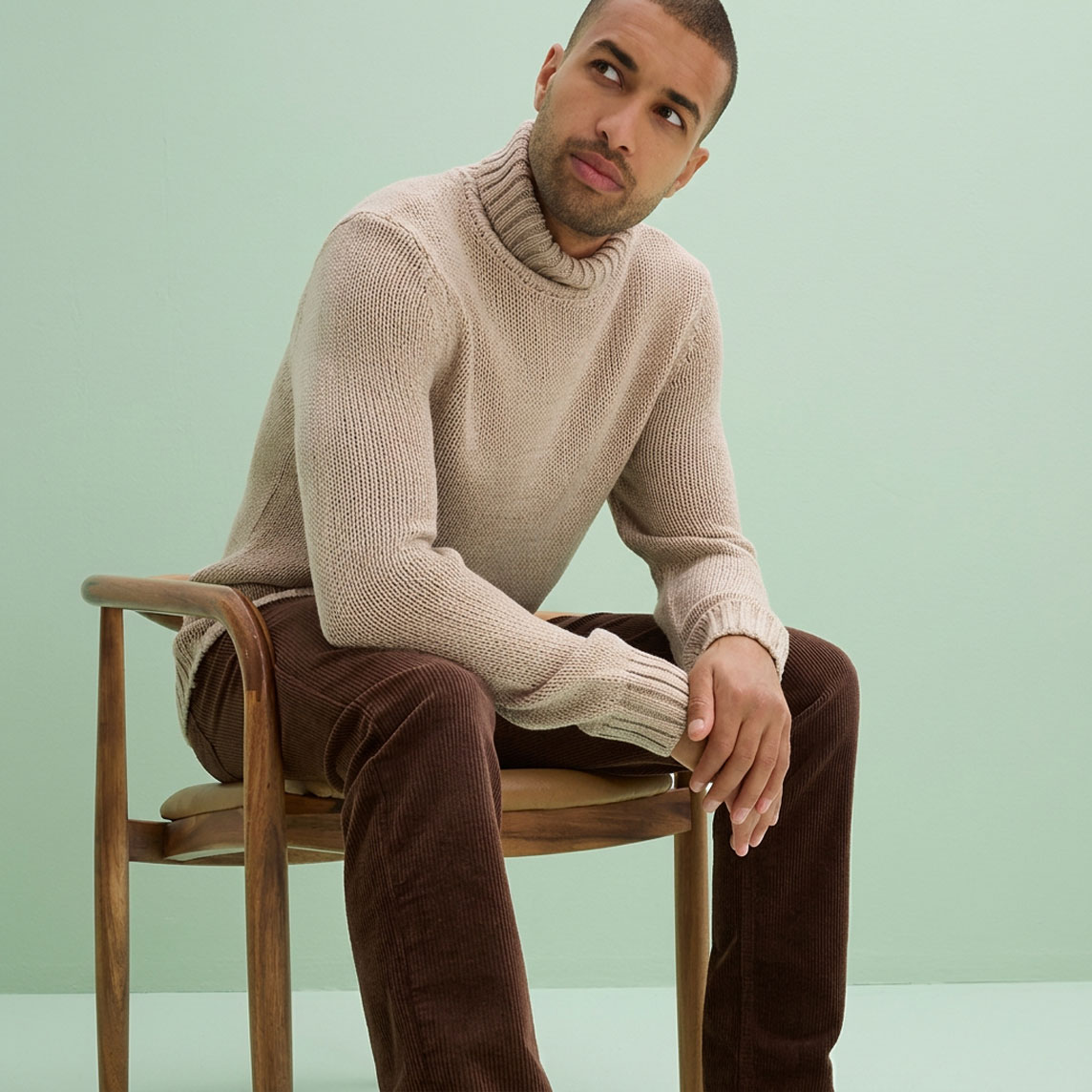 Ein gemütlicher beiger Rollkragenpullover und eine braune Cordhose.