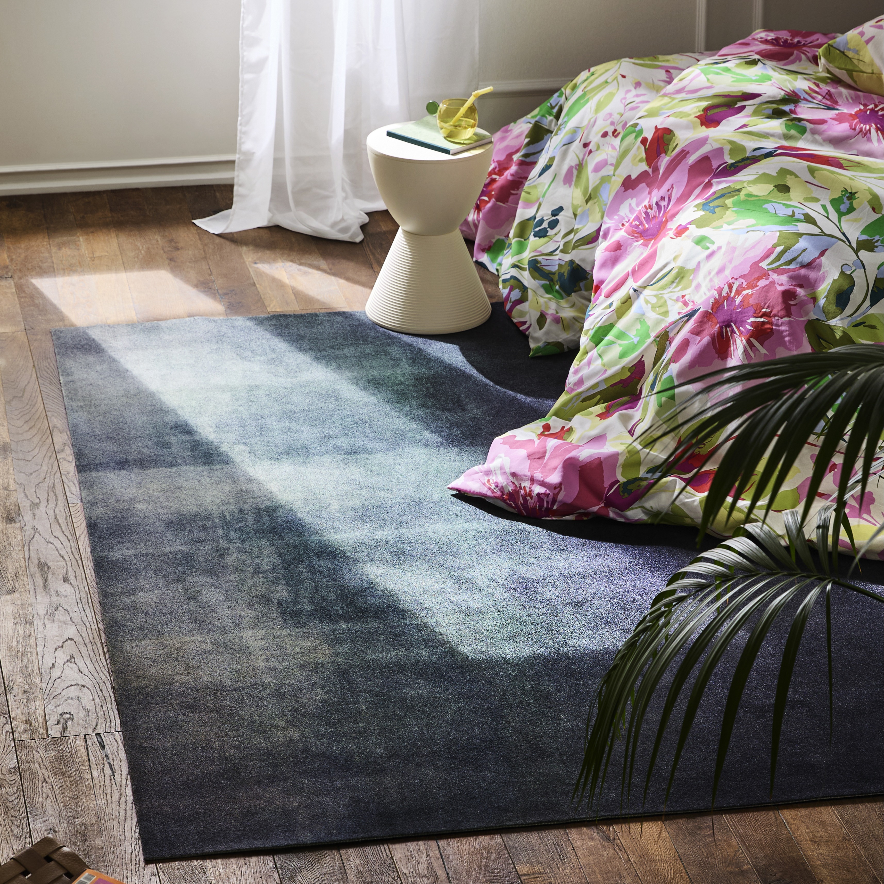 Buntes Blumenmuster auf Kissen und Decke verschönert das gemütliche Wohnzimmer mit stilvollem Teppich.