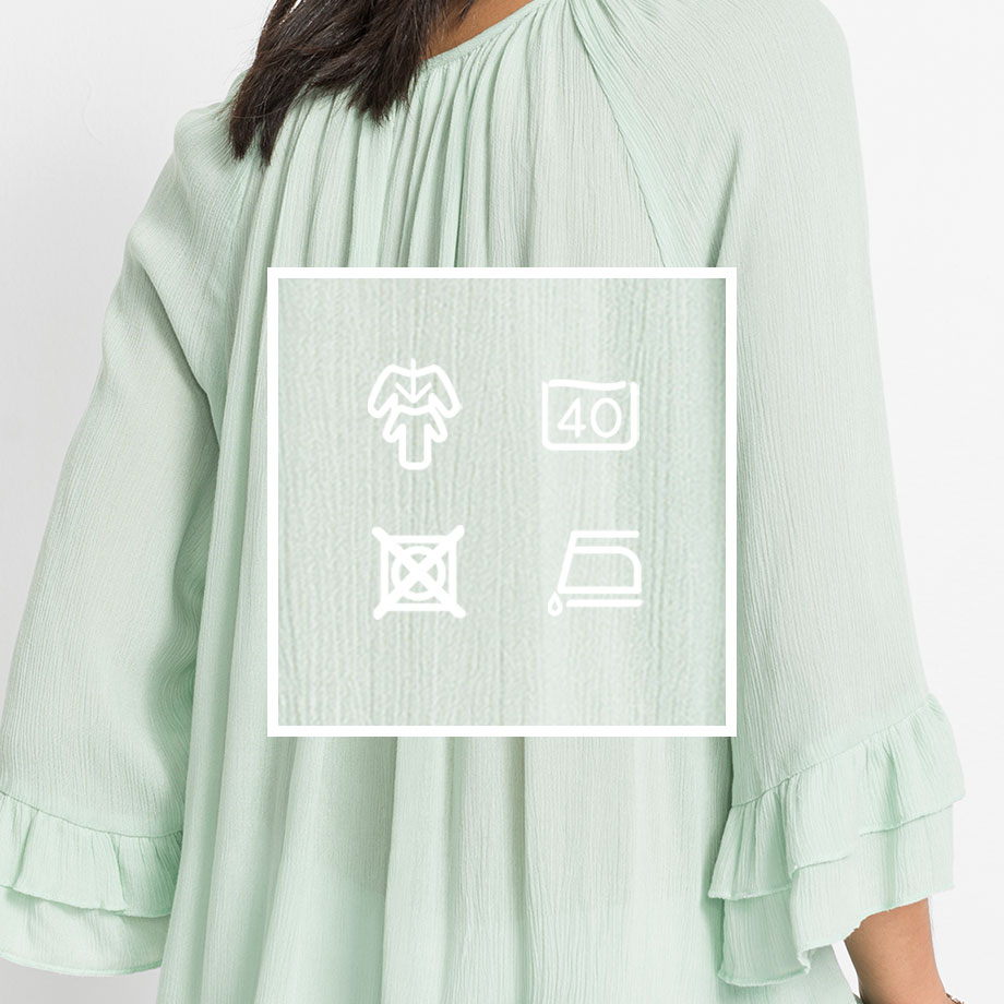 Pastellgrüne Bluse mit weiten Ärmeln und Pflegehinweisen für schonende Behandlung der zarten Textur.