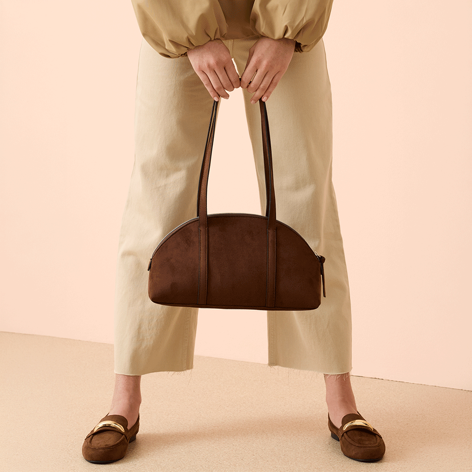 Elegante Hose in Beige, kombiniert mit brauner Handtasche und flachen Schuhen.