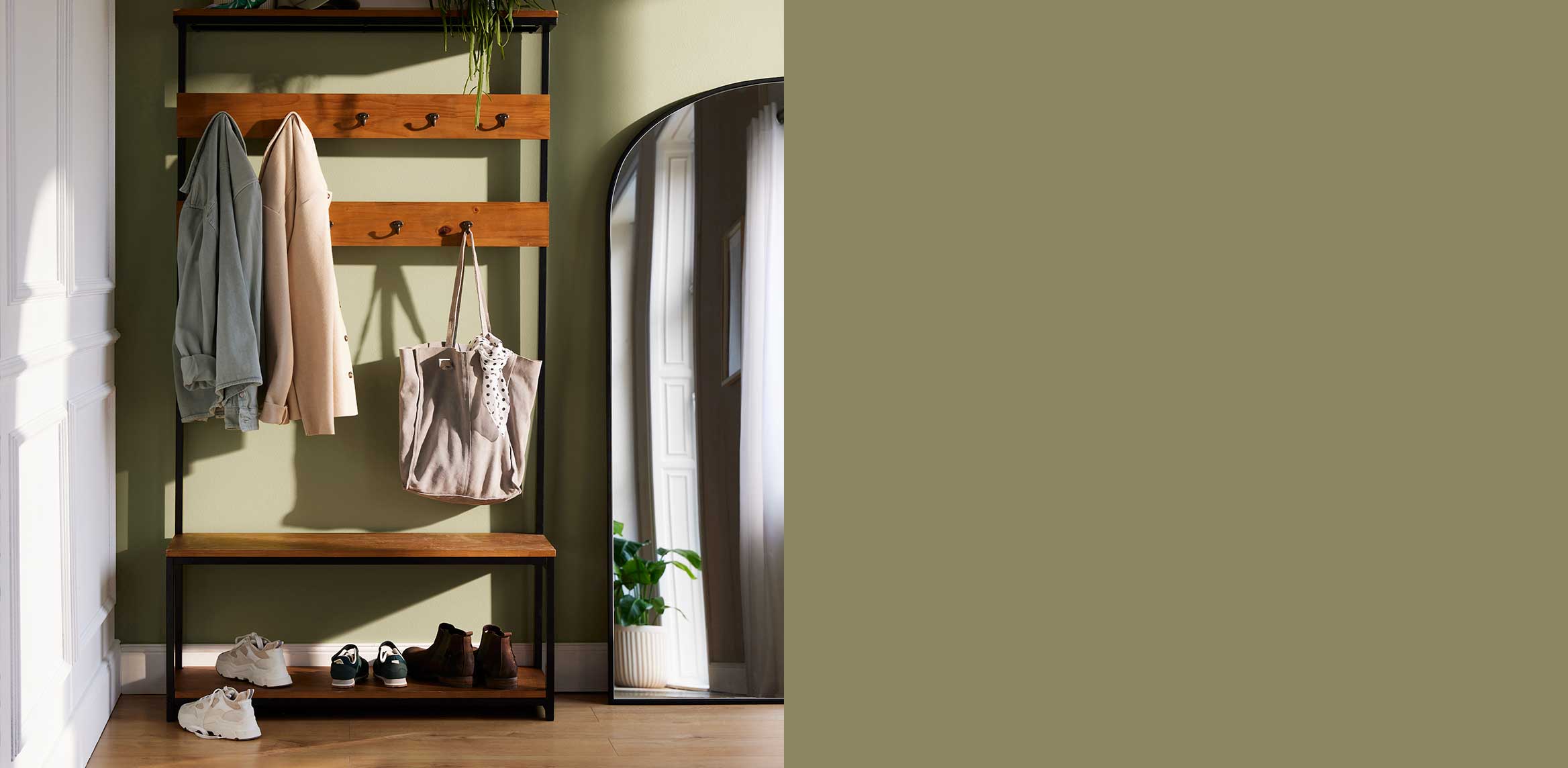 Eine offene Garderobe mit Holzregal zeigt Jacken, Taschen und Schuhe in natürlichen Farbtönen.