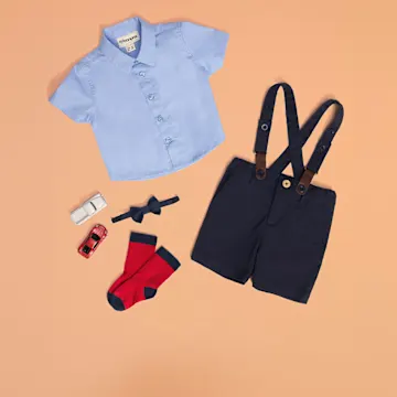 Blaues Hemd, schwarze Trägerhose und rote Socken für Babys.