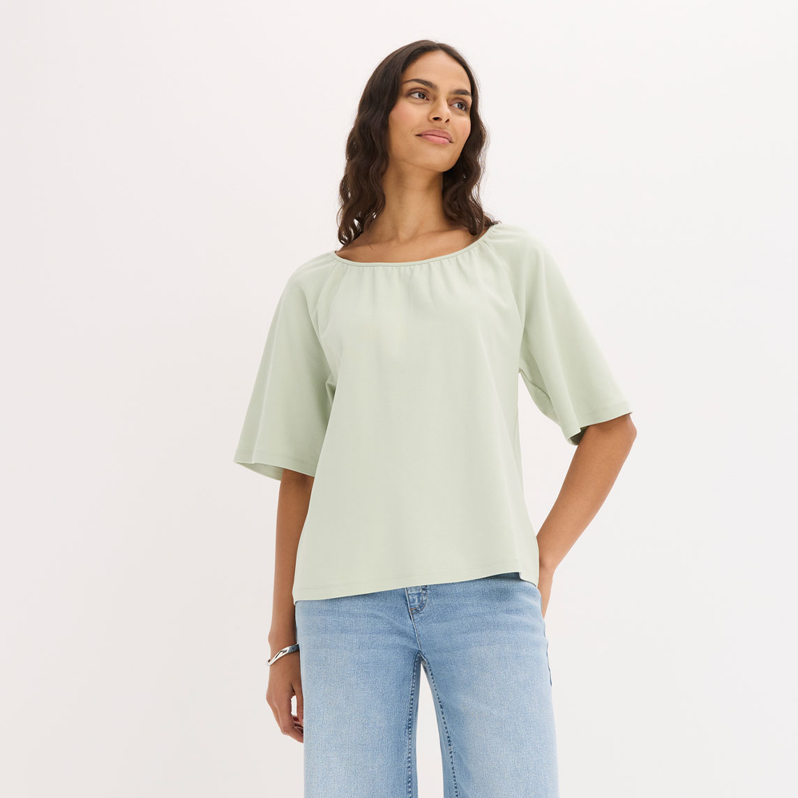 Elegante hellgrüne Bluse mit weiten Ärmeln, kombiniert mit lässigen Jeans.