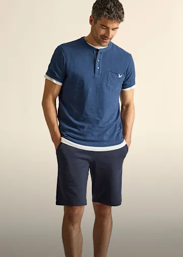 Lässiges blaues Henley-Shirt mit weißen Details über weißem Shirt und dunkler Hose.