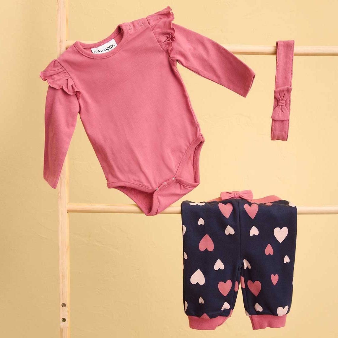 Süßes Babyset: Rosa Body und dunkelblaue Hose mit Herz-Muster.